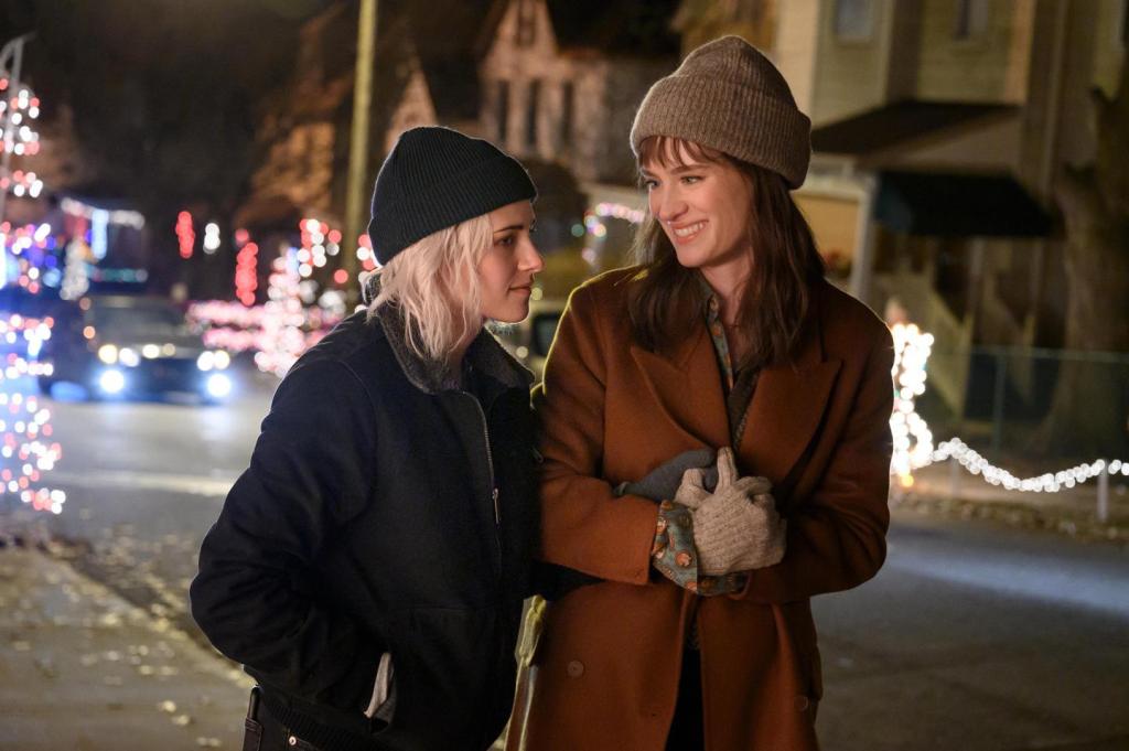 Kristen Stewart and Mackenzie Davis star in Happiest Season, walking outside holding hands.