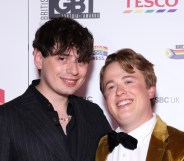 Jordan Sangha and Henry Southan poses with the Media Moment award. Jordan in a dark pinstripe suit and Henry in a gold suit with a black bowtie.