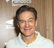 Mehmet Oz wearing a white polo top agains a wooden background