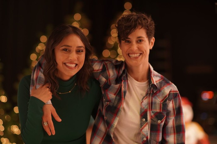 Merry & Gay still: two people with their arms around eachother and glowing lights in the background