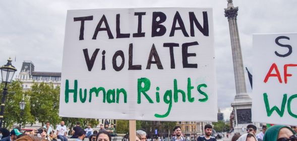 Person holds up a placard reading "Taliban violate human rights" at a protest against the Taliban in London