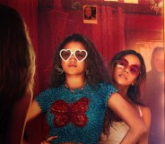 Time Cut still; two sisters posing in the mirror with glasses, a masked figure behind them