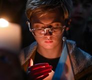 A person holds a candle and a trans flag at the vigil for murdered schoolgirl Brianna Ghey