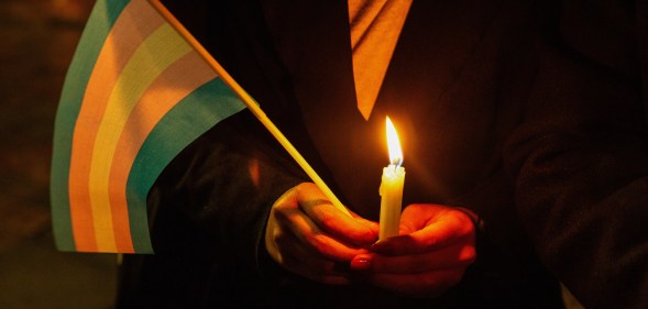 Trans Day of Remembrance Vigil, person holding a trans flag and a candle