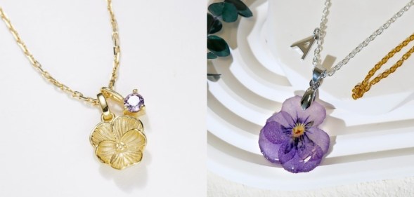 A gold violet necklace with a violet shaped charm and a violet coloured charm on the chain and a necklace of a dried violet flower sealed in resin.