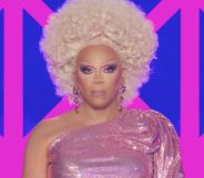 RuPaul in a pink dress with a stern face while hosting the final episode of drag race uk season 6