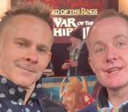 Lord of the Rings stars Dominic Monaghan and Billy Boyd stand next to each other as they smile intothe camera.