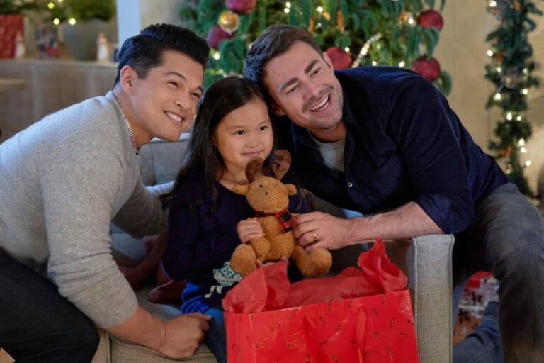 Two men and a little girl opening a reindeer present