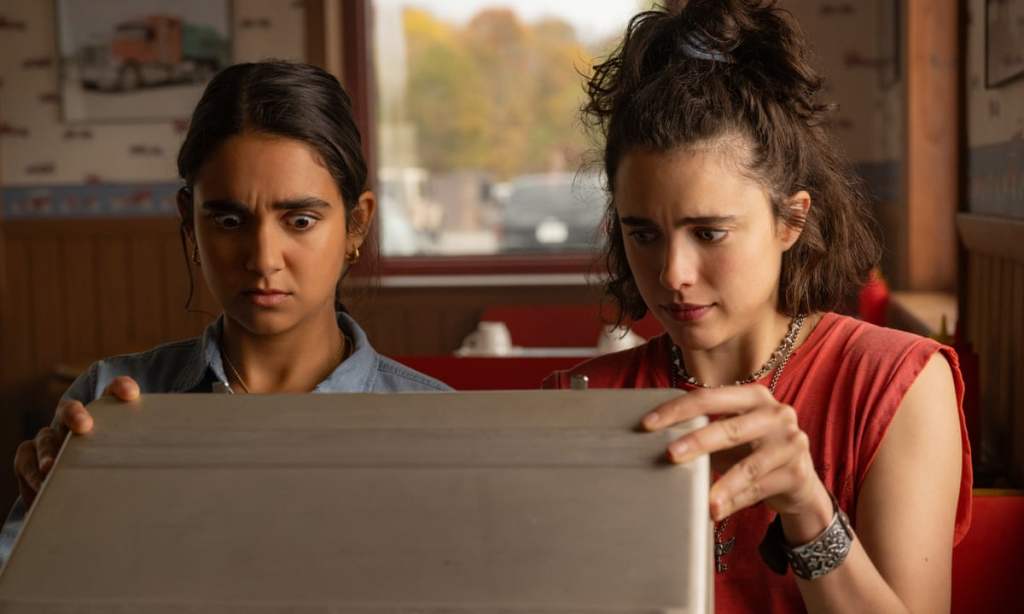 Drive-Away Dolls still: Geraldine Viswanathan and Margaret Qualley looking suprised at the contents of a briefcase.