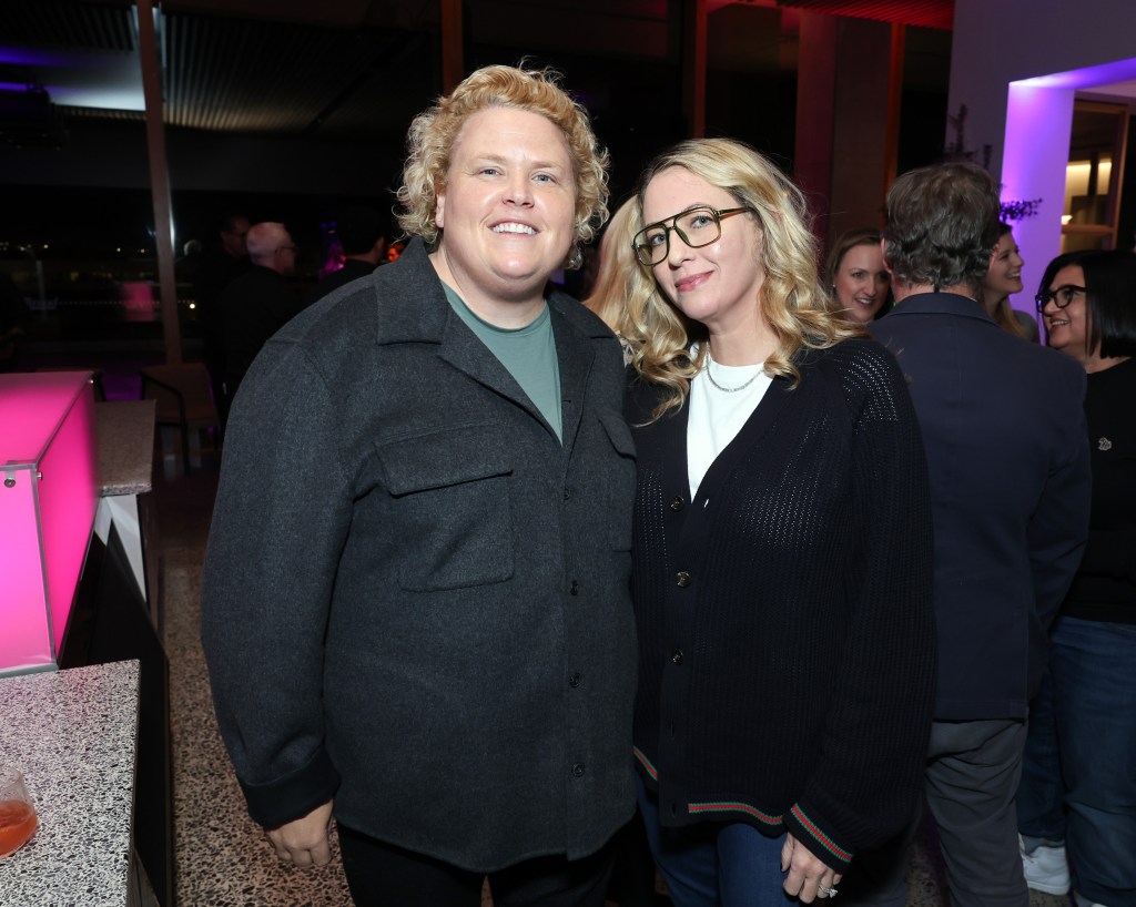 Fortune Feimster, wearing a black overshirt and green t shirt, and Jacquelyn Smith, wearing a black cardigan and a white t shirt.