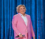 Fortune Feimster on stage in her Netflix special ‘Crushing It’ wearing a pink suit.