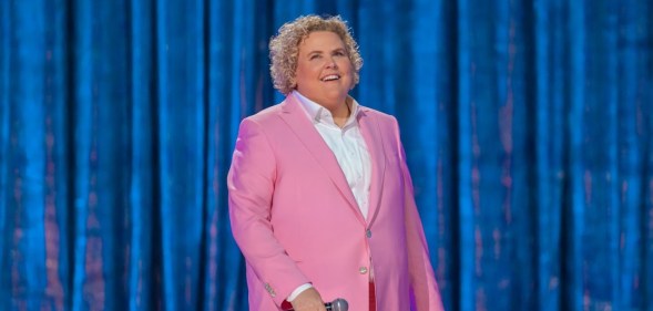 Fortune Feimster on stage in her Netflix special ‘Crushing It’ wearing a pink suit.