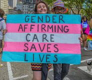 A person holding a sign that says "gender-affirming care saves lives"