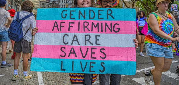 A person holding a sign that says "gender-affirming care saves lives"