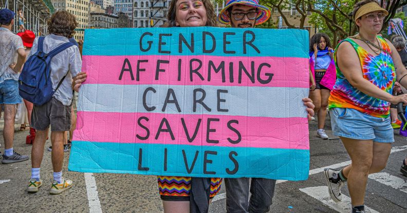 A person holding a sign that says "gender-affirming care saves lives"