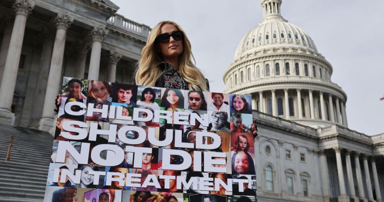 Paris Hilton holding a sign saying "children should not die in treatment"