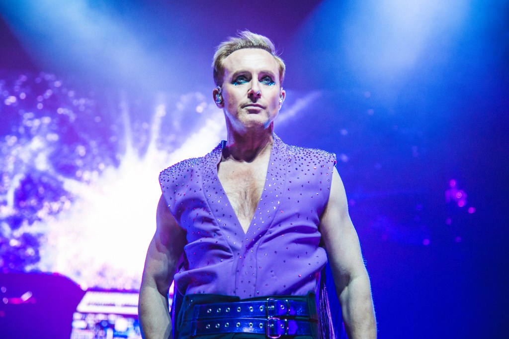 Ian "H" Watkins of Steps performs at The O2 Arena. He's wearing a low-V purple shirt covered in gems.