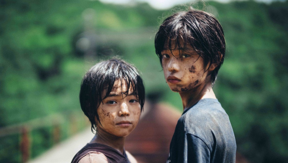 Monster still: Hinata Hiiragi and Sōya Kurokawa covered in mud looking to the camera.