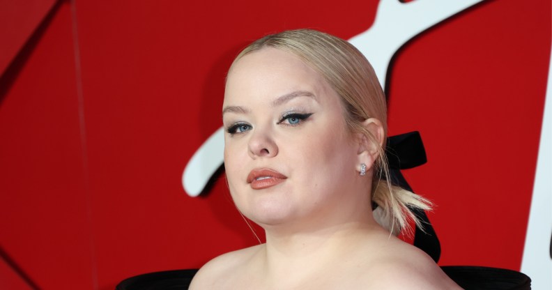 Nicola Coughlan attends The Fashion Awards , in a black open shoulder dress with her blonde hair tied back in a black bow