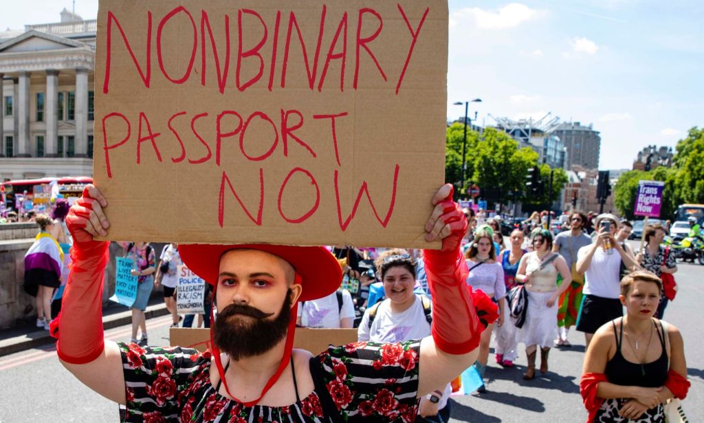 A person holds up a sign reading 'Non-binary passport now'