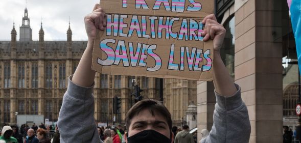 A person holding a sign that reads "trans healthcare saves lives."