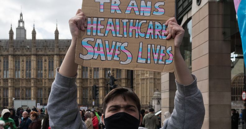 A person holding a sign that reads "trans healthcare saves lives."