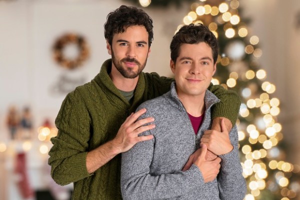 The Christmas Setup; two men hugging in front of a lit up Christmas tree