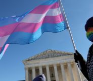 A person outside the Supreme Court waving a trans flag.