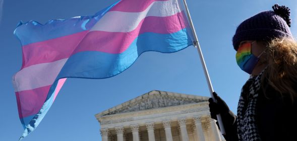 A person outside the Supreme Court waving a trans flag.