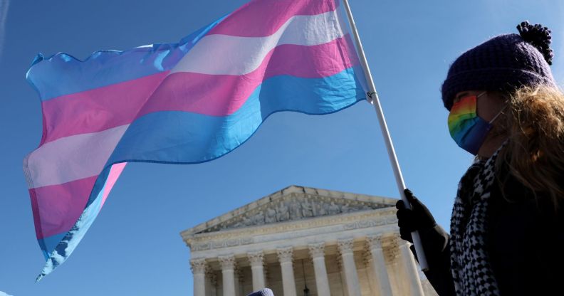 A person outside the Supreme Court waving a trans flag.