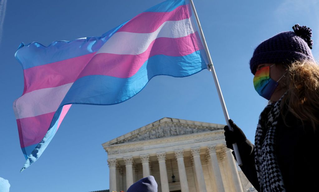 A person outside the Supreme Court waving a trans flag.