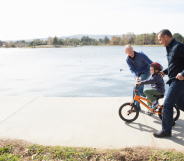 A gay couple teaching their child to ride a bike.