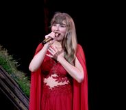 Taylor Swift wearing a red dress and holding a mic at the Vancouver BC Stadium for the final show of the Eras Tour