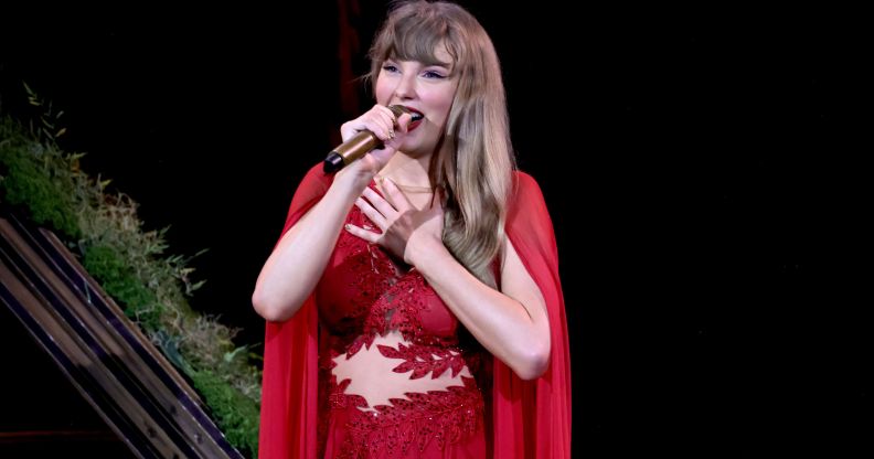 Taylor Swift wearing a red dress and holding a mic at the Vancouver BC Stadium for the final show of the Eras Tour