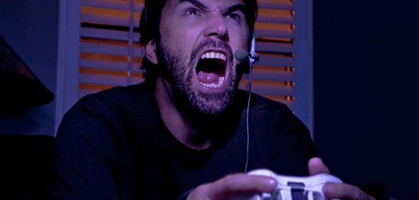 A man holding a gaming controller and screaming.