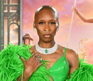 Cynthia Erivo on a red carpet at a Wicked premiere in a green dress and matching feather boa staring at the camera