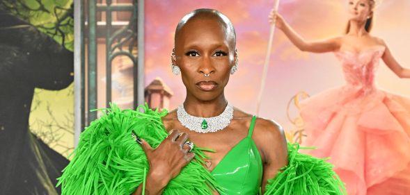 Cynthia Erivo on a red carpet at a Wicked premiere in a green dress and matching feather boa staring at the camera