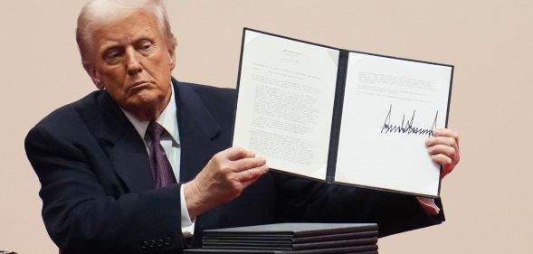 US President Donald Trump holds up an executive order after signing it during an indoor inauguration parade at Capital One Arena on January 20 2025 in Washington, DC