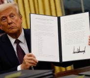 Donald Trump holding up a folder containing an executive order.