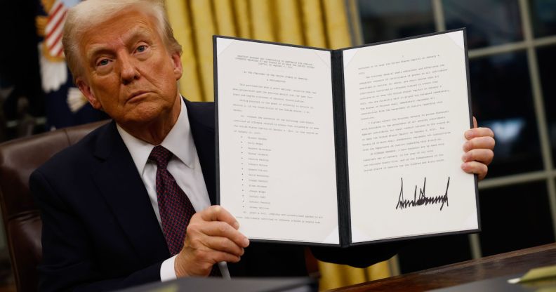 Donald Trump holding up a folder containing an executive order.