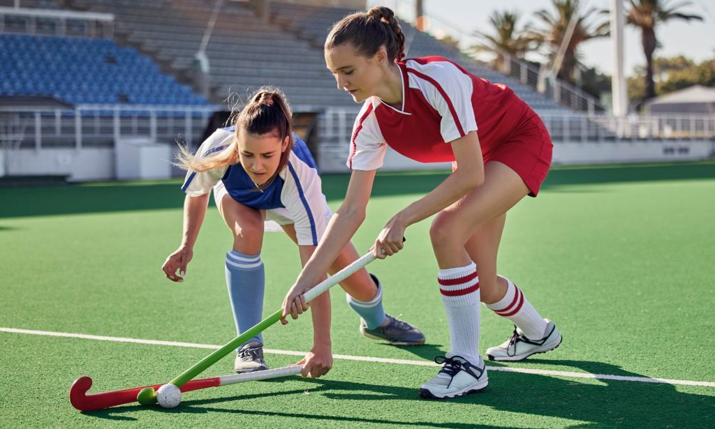 Two women competing in a hockey game