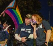 Transgender athlete supporter Kyle Harp, left, of Riverside holds the progress pride flag next to "Save Girls Sports" supporters Lori Lopez and her dad Pete Pickering on December 19, 2024 (Getty)