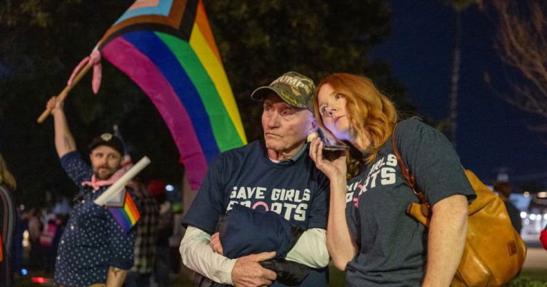 Transgender athlete supporter Kyle Harp, left, of Riverside holds the progress pride flag next to "Save Girls Sports" supporters Lori Lopez and her dad Pete Pickering on December 19, 2024 (Getty)