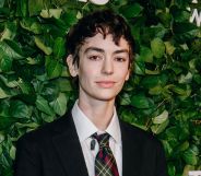 Jack Haven at a Vanity Fair red carpet event standing in front of greenery, wearing a black blazer and white shirt