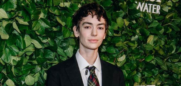 Jack Haven at a Vanity Fair red carpet event standing in front of greenery, wearing a black blazer and white shirt