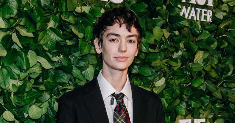 Jack Haven at a Vanity Fair red carpet event standing in front of greenery, wearing a black blazer and white shirt