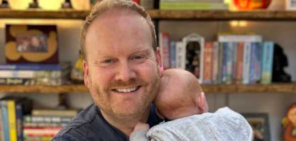 Kevin smiles as he holds his baby girl close to him.