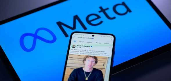 An image showing a screen with Meta's logo on it and a phone on top of it with an image of its founder, Mark Zuckerberg.