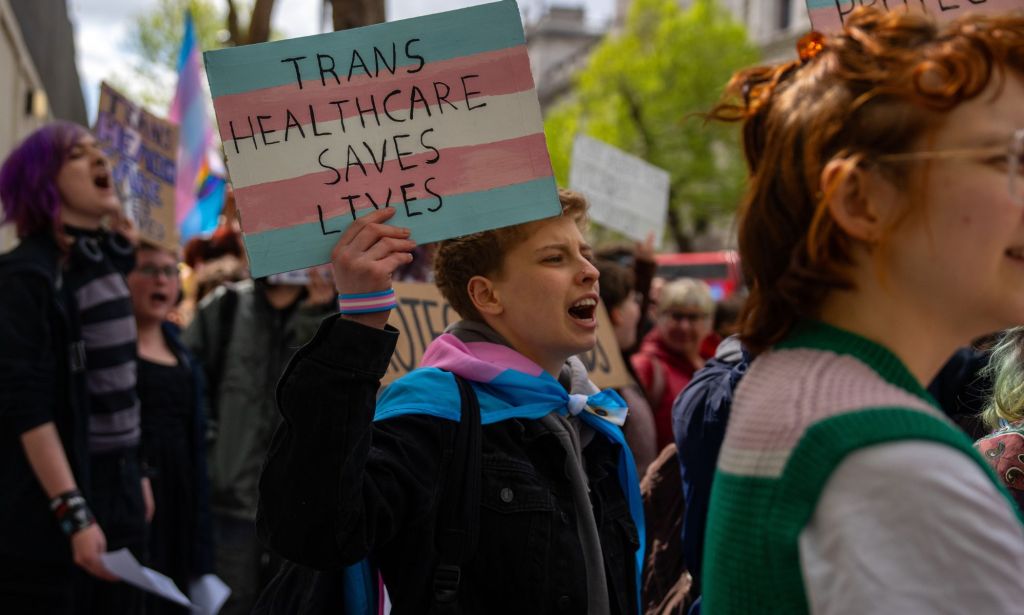 Protestors holding signs that read "trans healthcare saves lives."