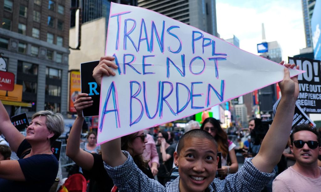 A person holding a sign up that reads "trans ppl are not a burden."